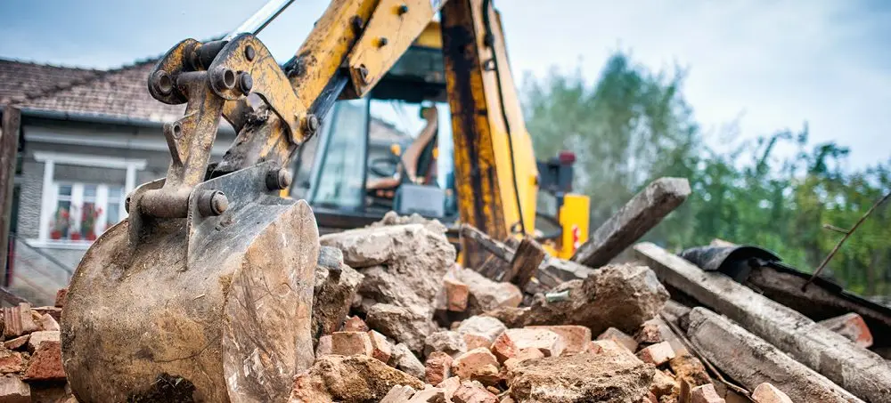 Excavator clearing demolition debris and preparing a construction site for redevelopment in Brisbane